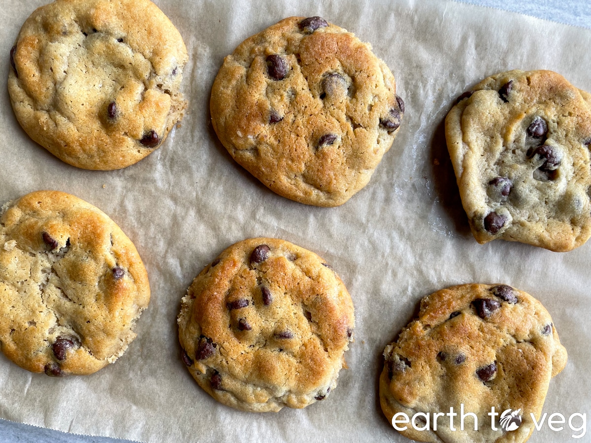 baked chocolate chip cookies lying on a sheet of parchment paper.