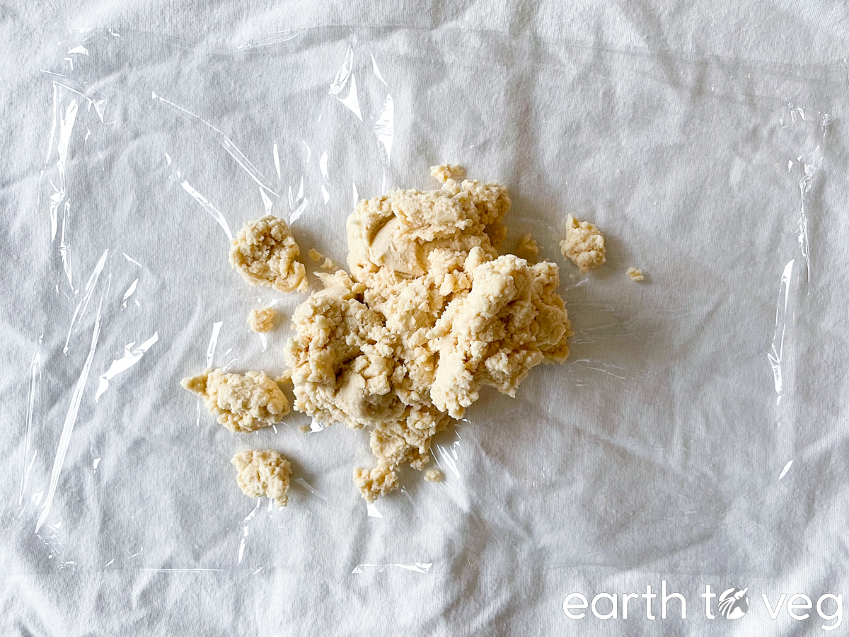 Cookie dough is dropped onto a piece of plastic wrap.