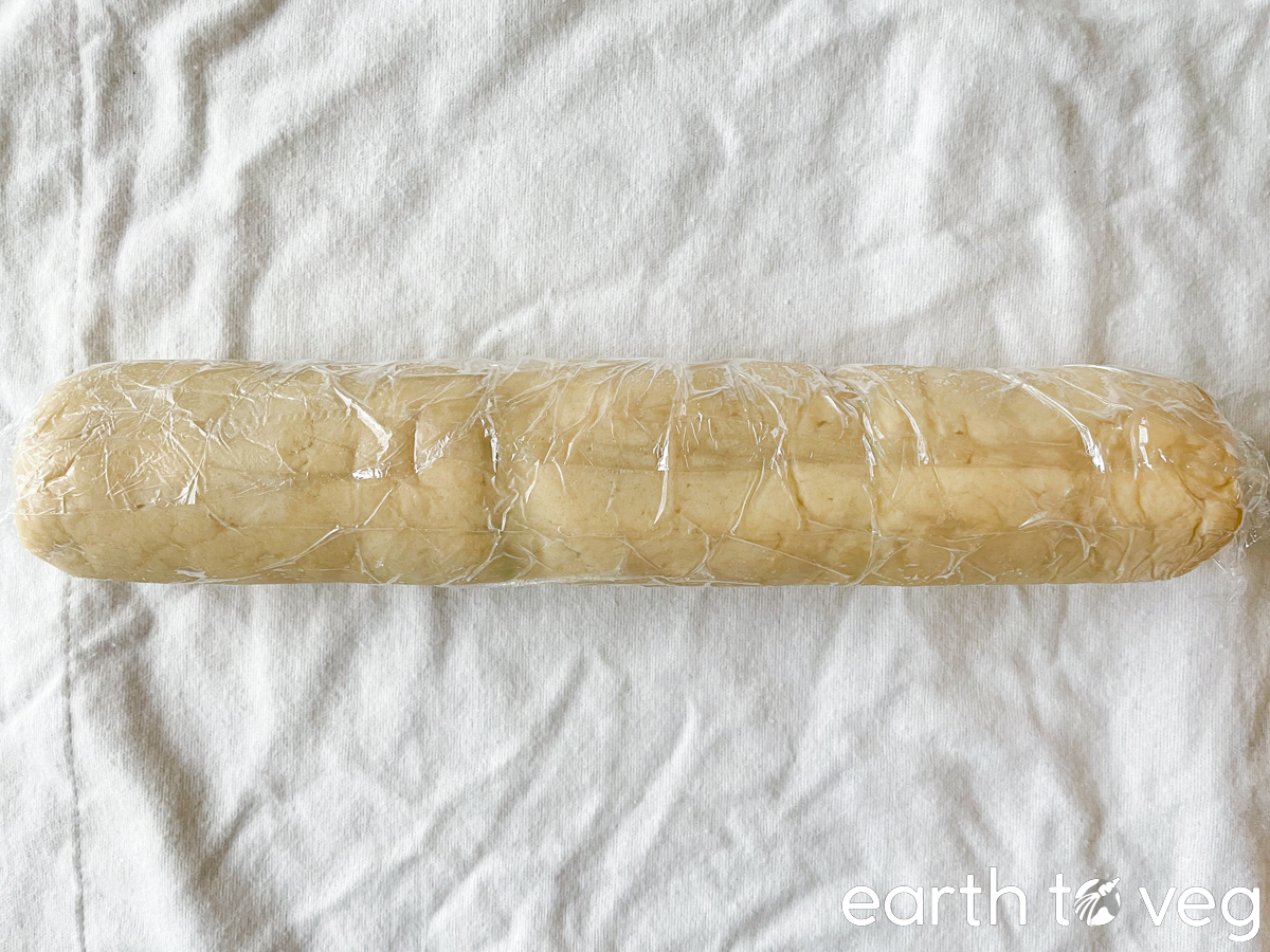 A tube of cookie dough wrapped in plastic wrap.