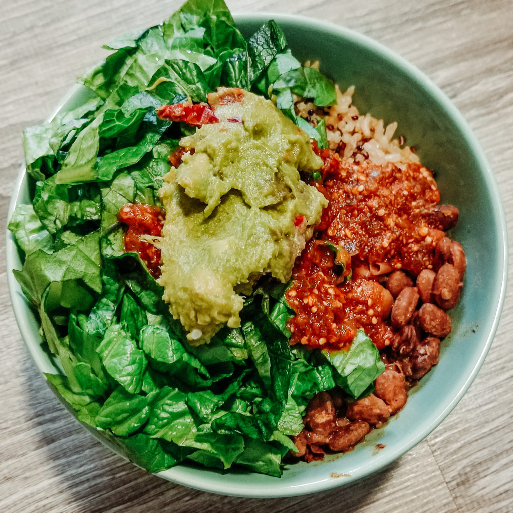 chipotle pinto bean burrito bowl with lettuce, guacamole, and hot sauce