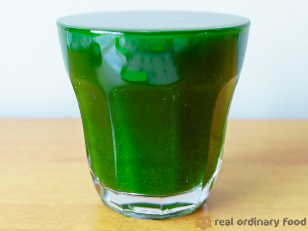 A glass filled to the brim with homemade pandan juice.