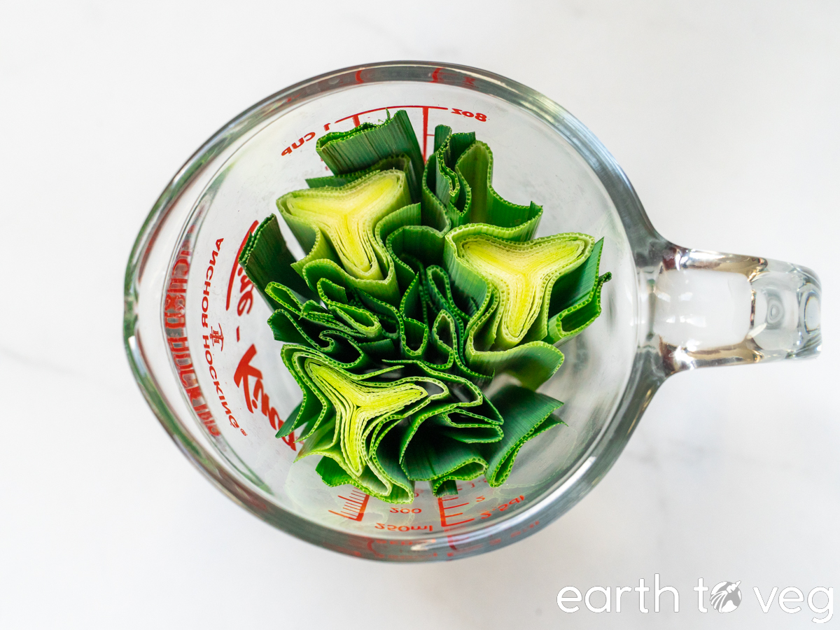 A top-down view of a measuring cup filled with chopped pandan leaves.