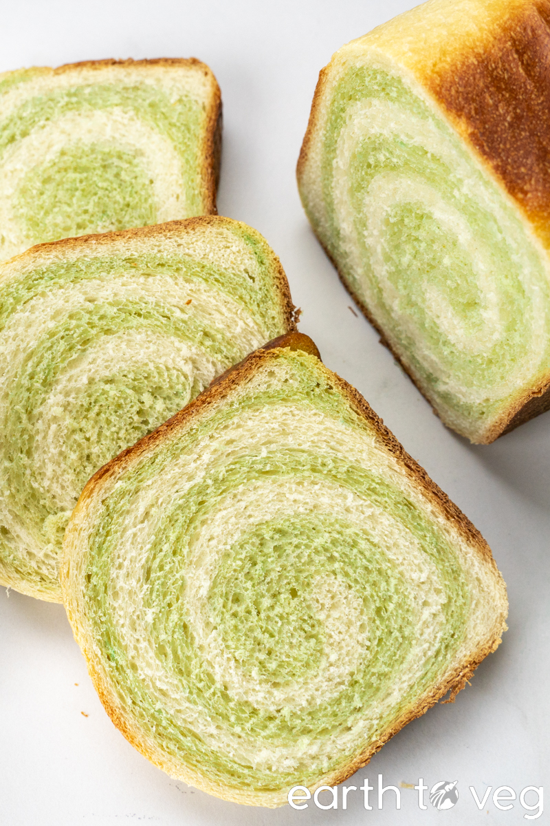 A top-down view of a pandan coconut loaf, with three slices sliced off.