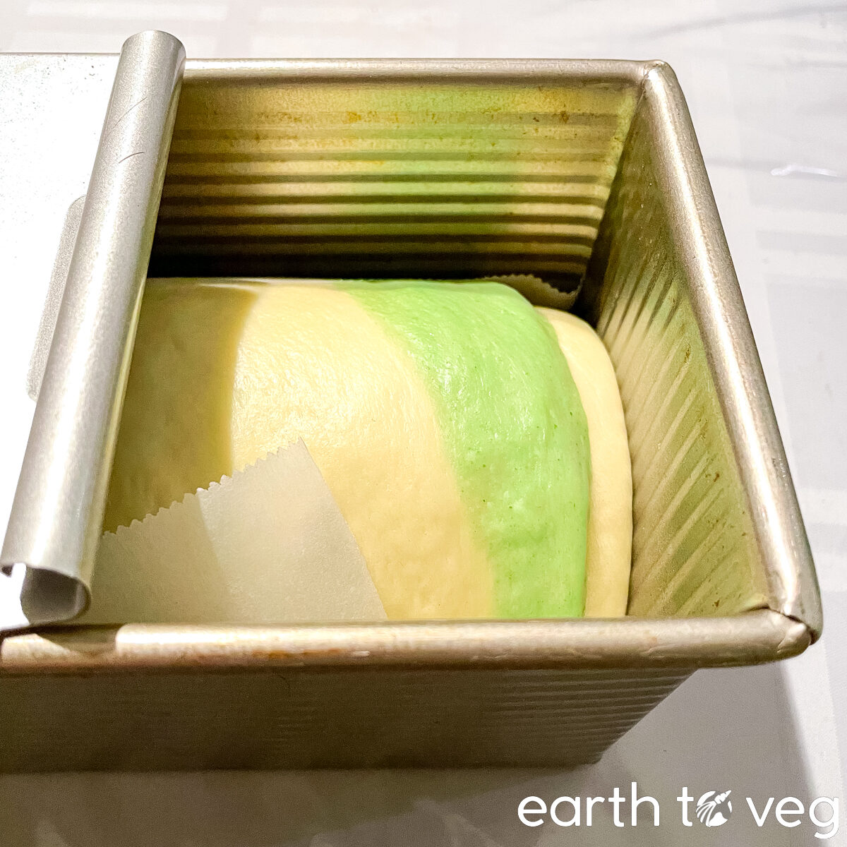 Fully-risen pandan swirl loaf in a metal baking pan.