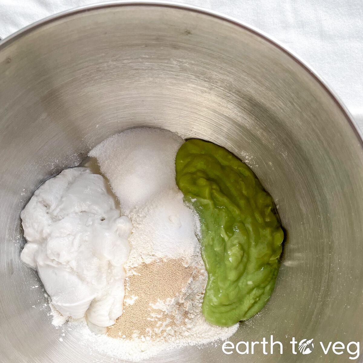 The ingredients for pandan bread sit in a stainless steel mixing bowl.