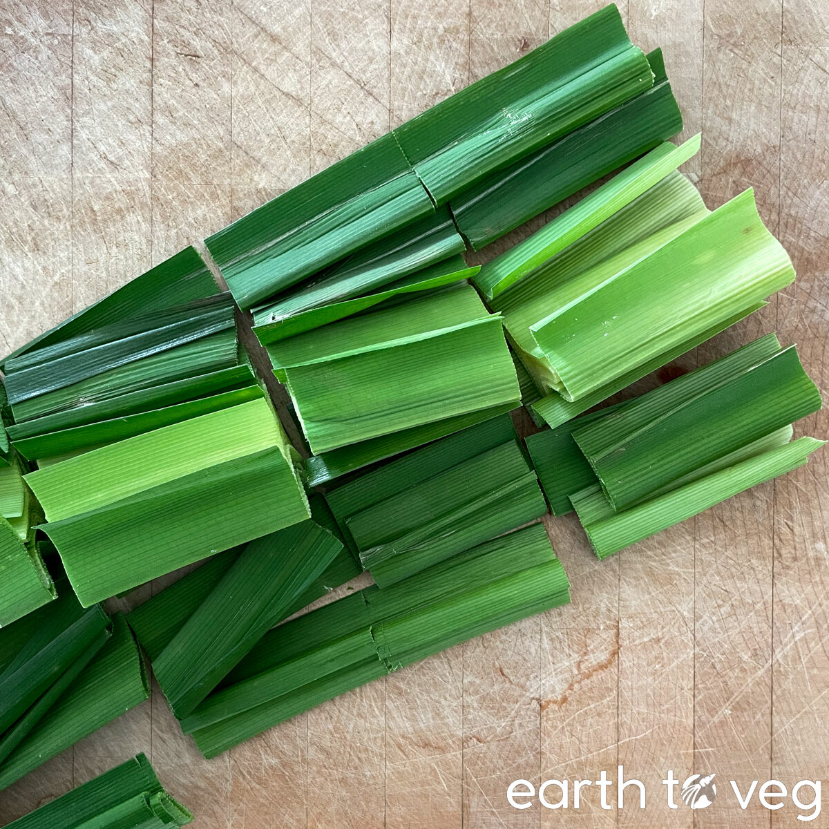 Chopped pandan leaves rest on a wooden cutting board.