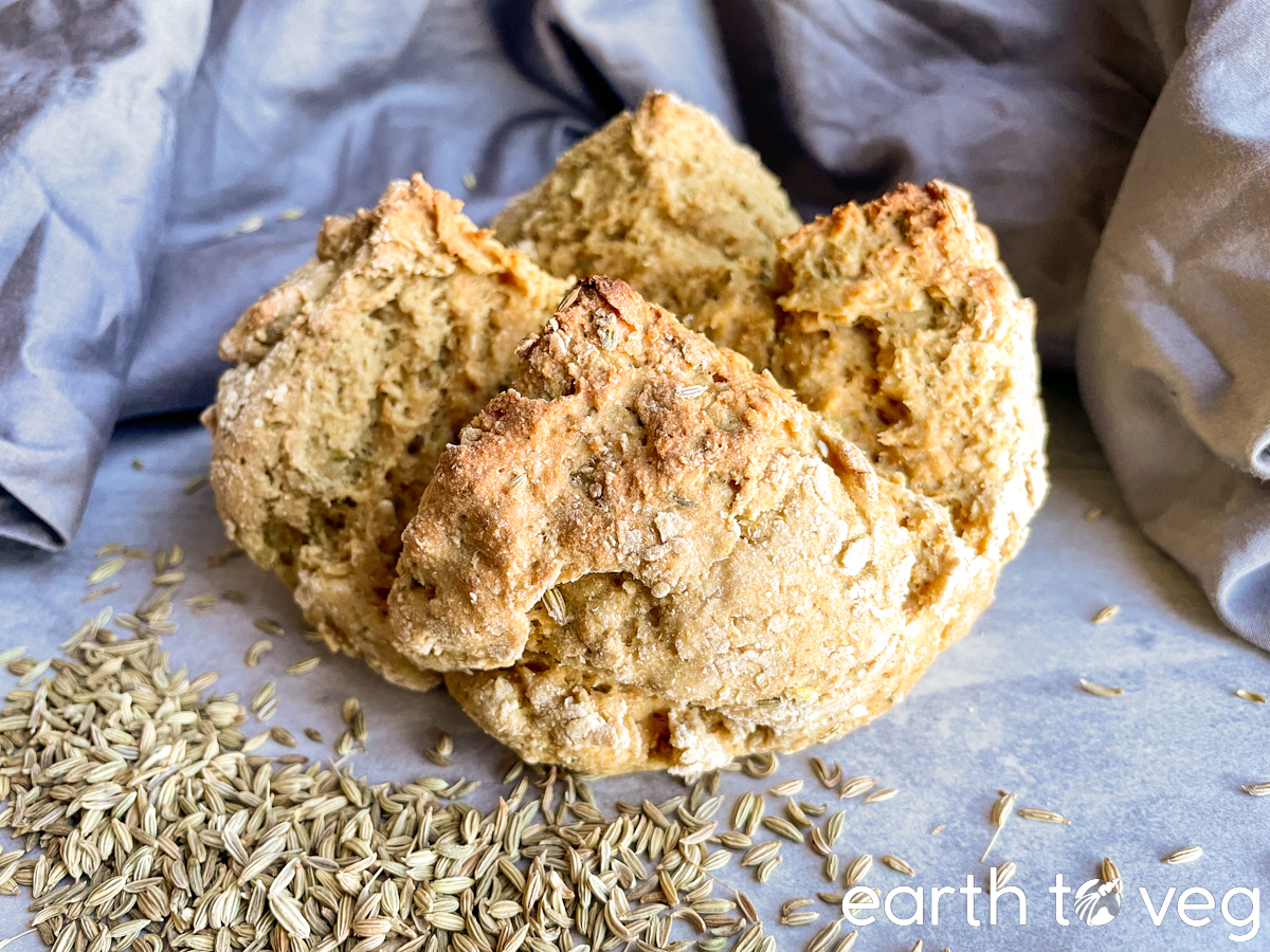 boule of fennel irish soda bread on a tile surface with whole fennel seeds scattered on one side