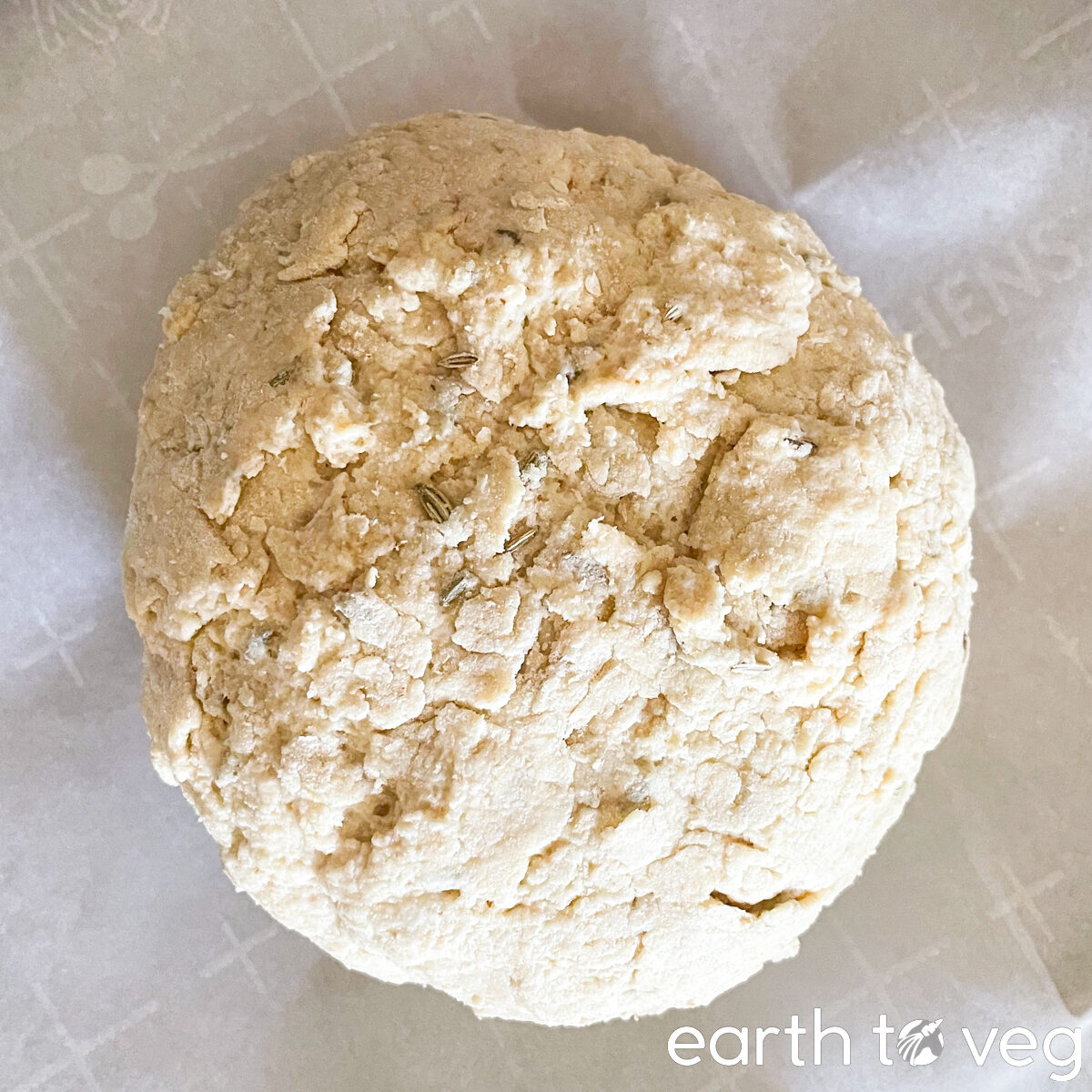 An unbaked round loaf of soda bread dough sits on parchment paper.