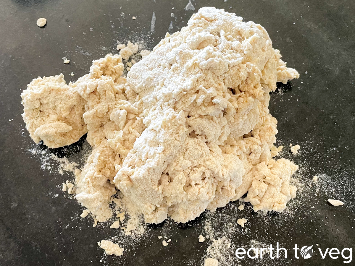 A messy bunch of Irish soda bread dough has been turned out onto a black countertop.