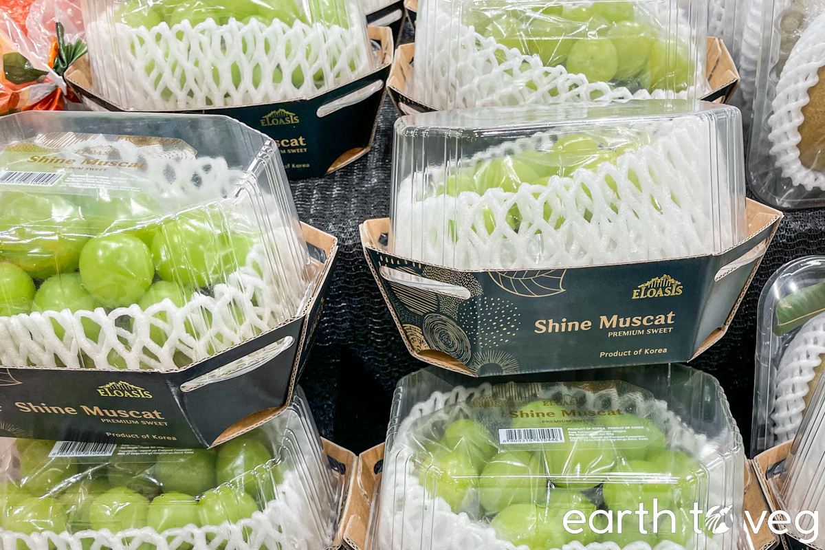 Boxes of ELOASIS brand Korean shine muscat grapes on a supermarket shelf.