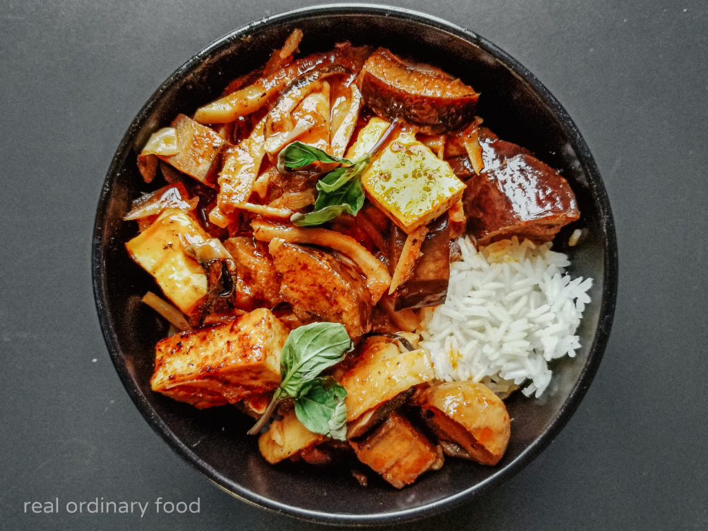 Thai vegan jungle curry in a black bowl on a grey table.