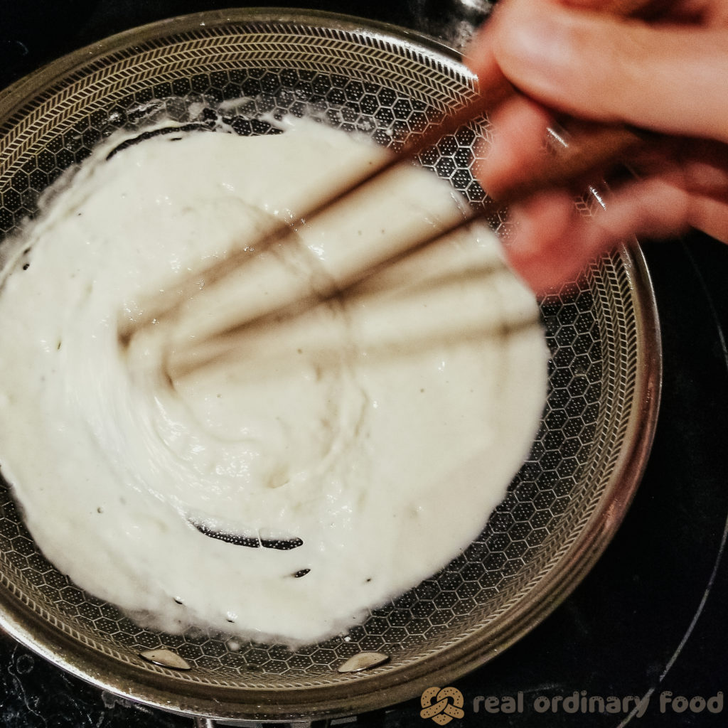 Chopsticks whisk through flour and water in a small saucepan to make water roux tangzhong.