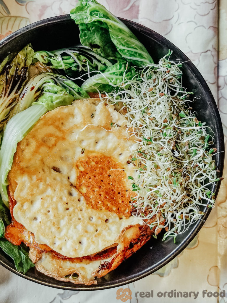 vegan fried eggs and alfalfa sprouts over baby bok choy