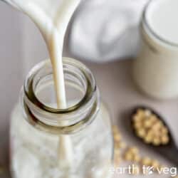 soy milk being poured into a glass bottle.