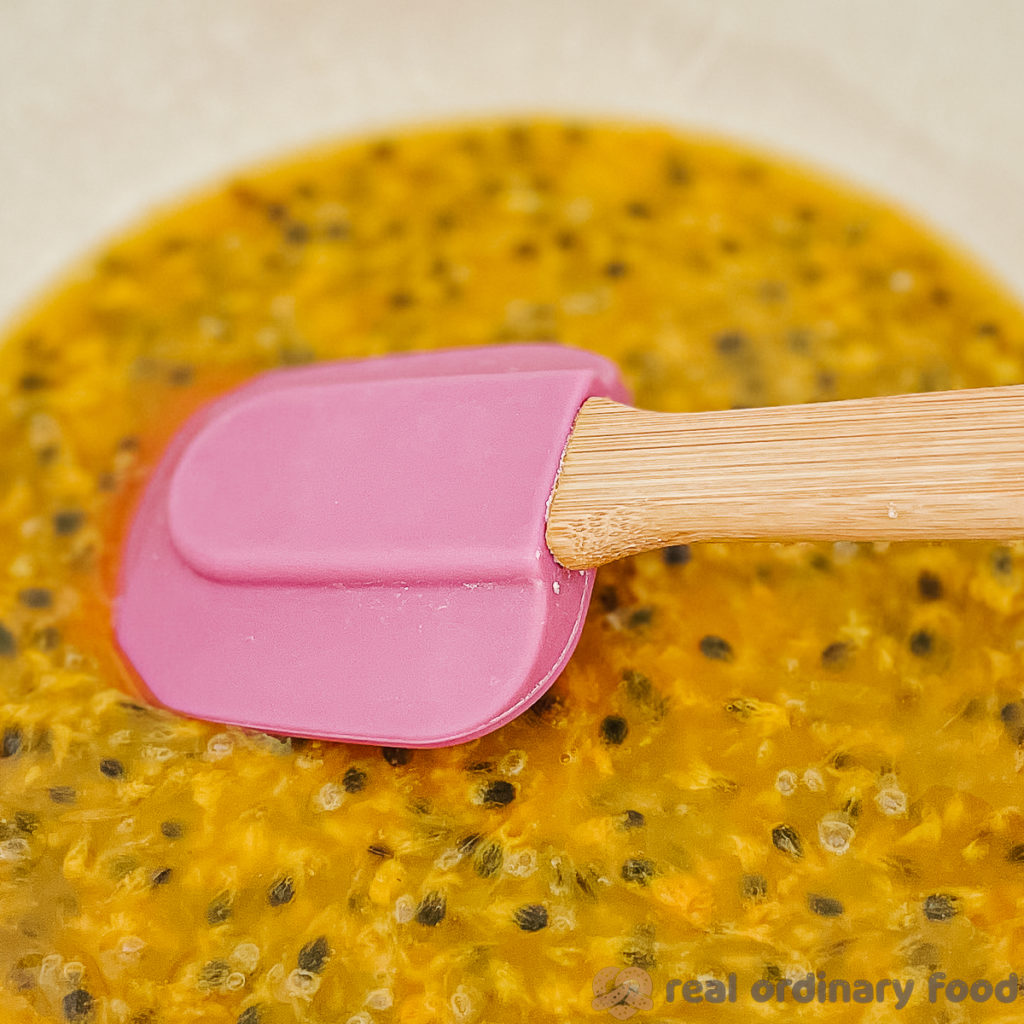 stirring passion fruit pulp wtih a rubber spatula