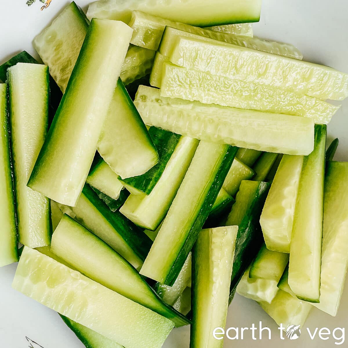 Sliced cucumber strips tossed in a white bowl.