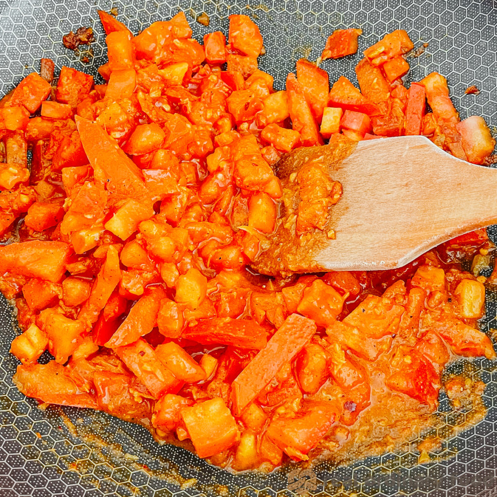 Chopped tomatoes simmer in a nonstick wok.
