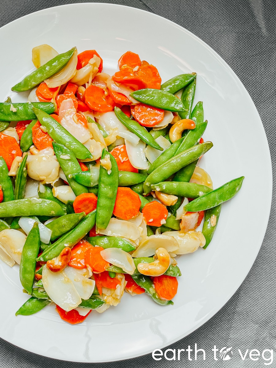 Sautéed lily bulbs with snow peas, cashews, and carrots on a porcelain plate.