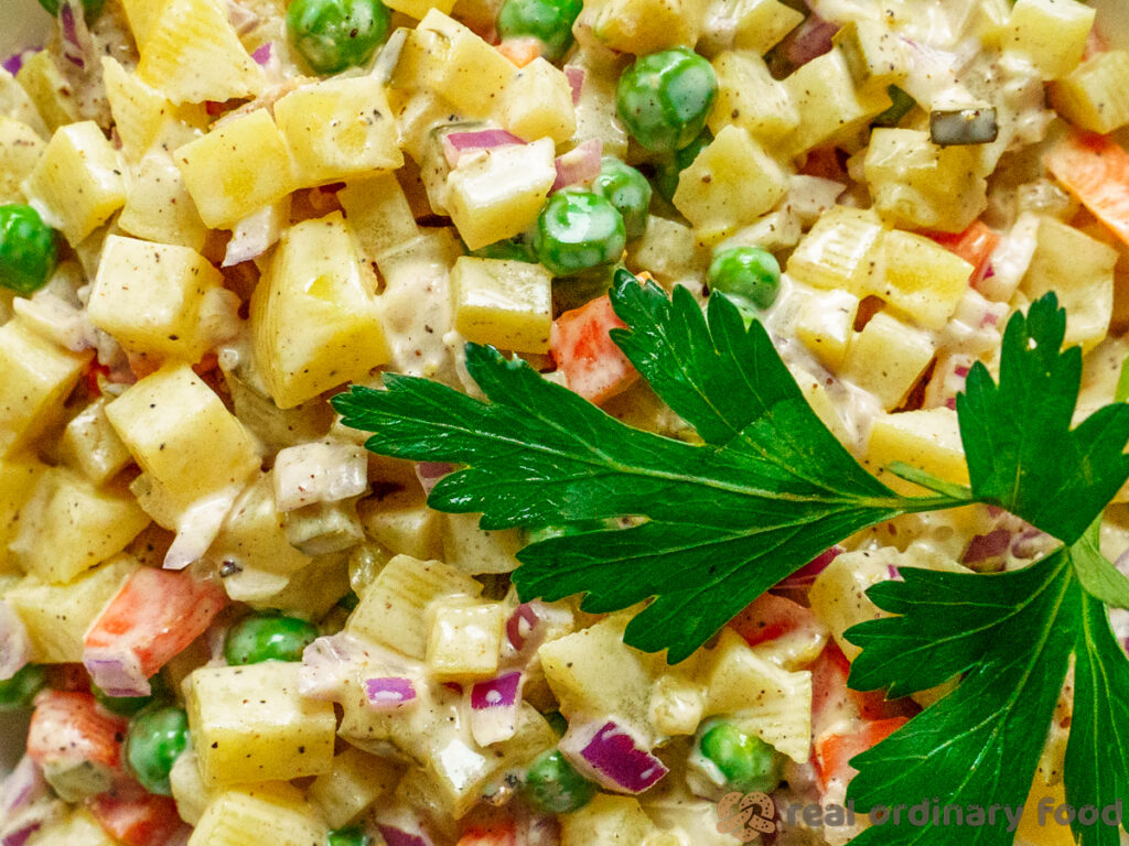 Vegan Olivier salad with a sprig of parsley leaf on the side.