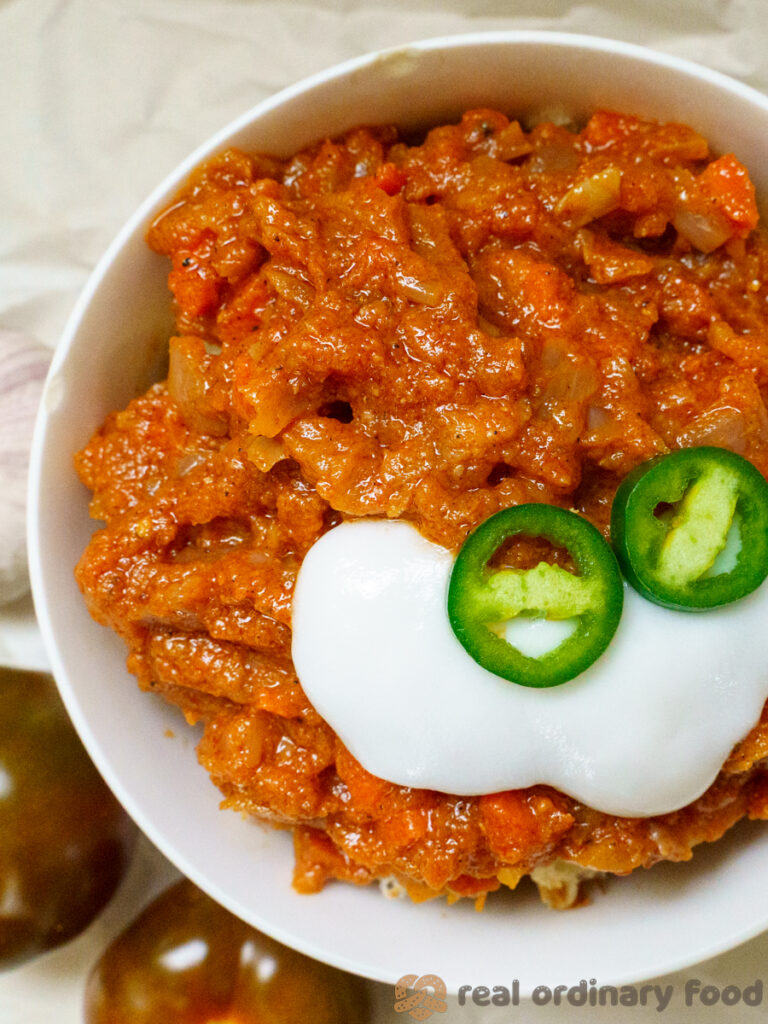 bowl of silsi eritrean tomato sauce topped with yogurt and jalapeno pepper