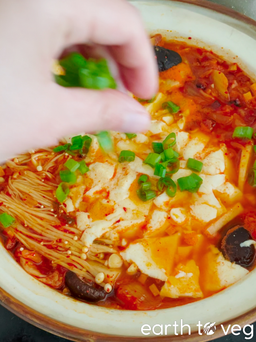 Scallions are sprinkled over the bubbling sundubu jjigae for a finishing touch.