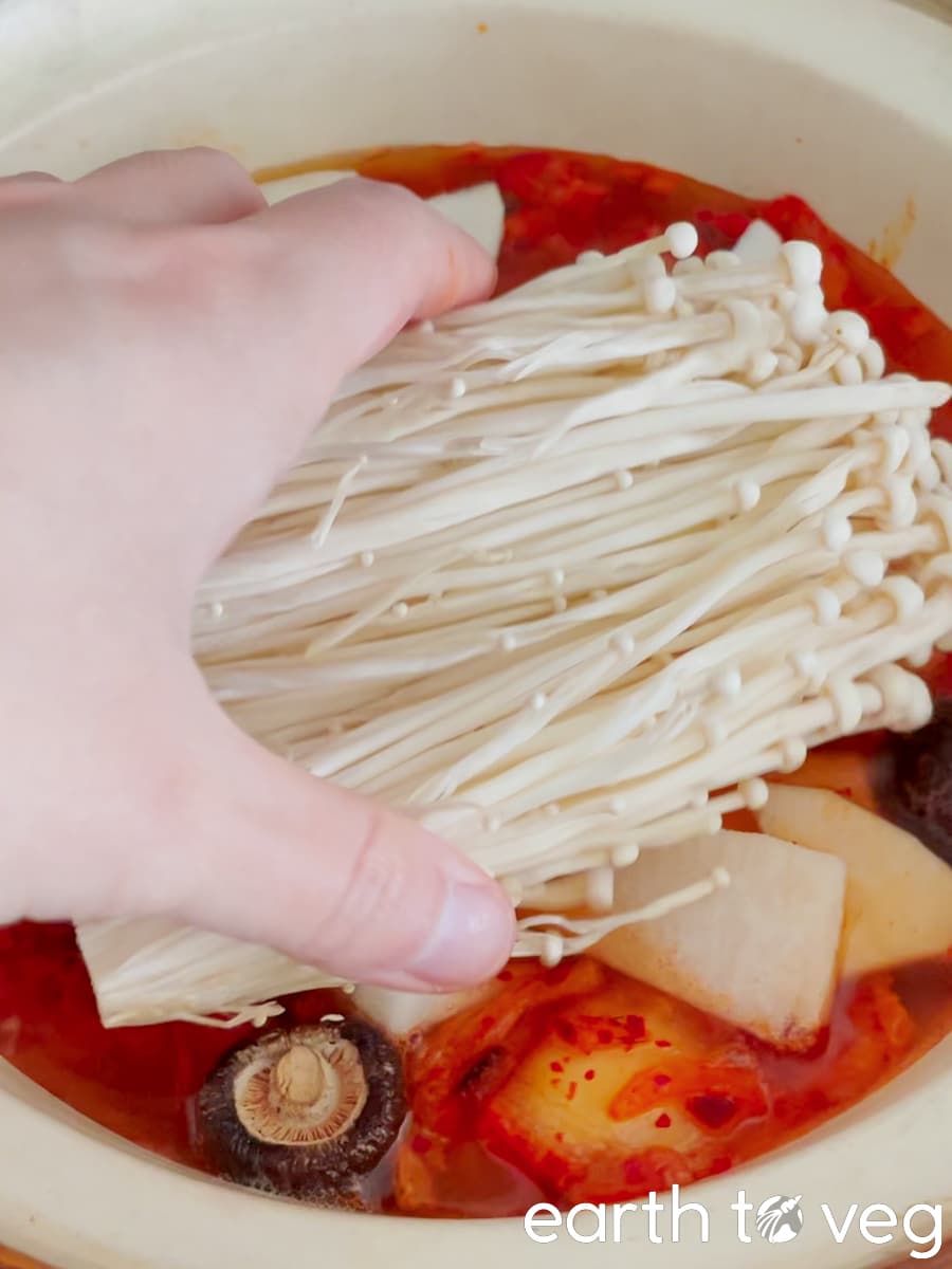 Enoki mushrooms are nestled into the spicy jjigae.