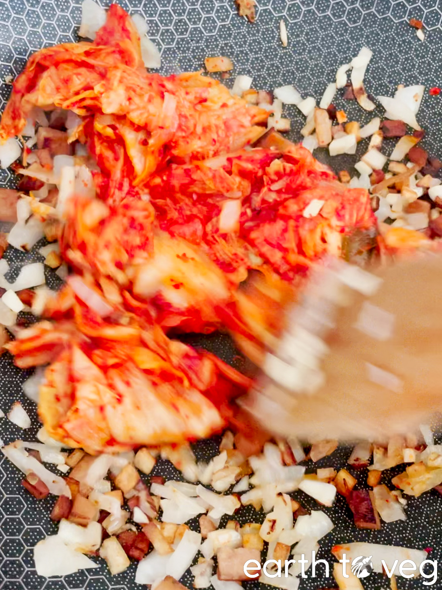 Kimchi is stirred in with the other ingredients in the wok.