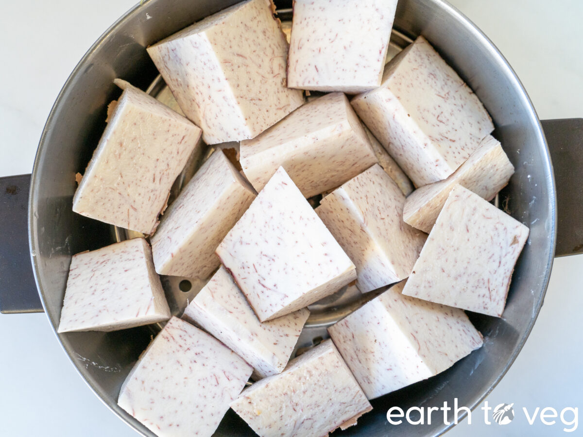 Large chunks of uncooked taro are crowded into a small stock pot.