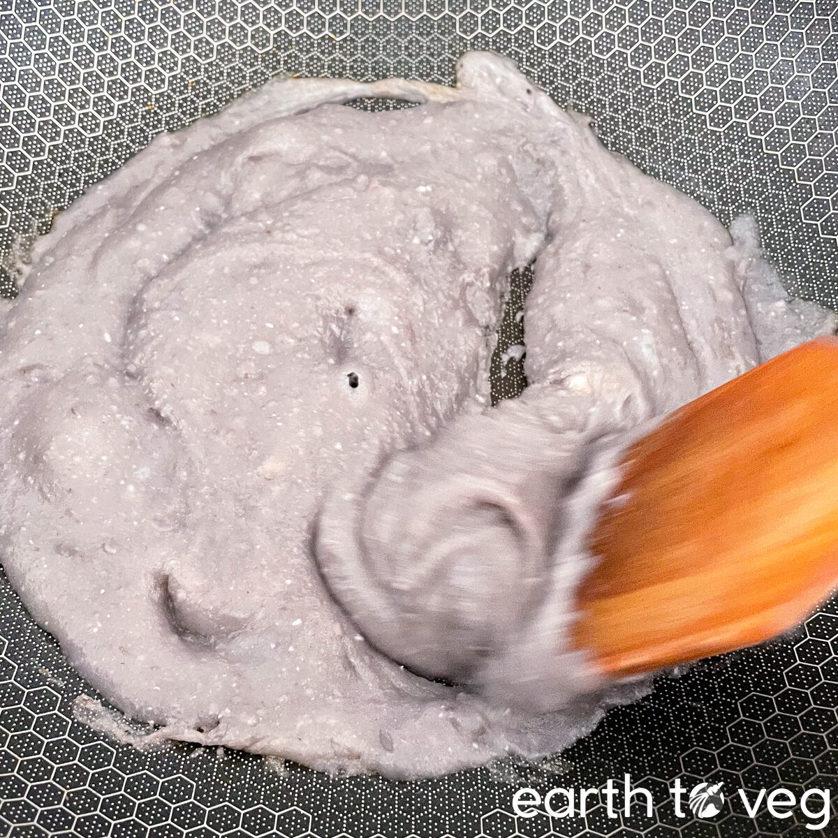 The taro paste is stirred around with a spatula in a non-stick wok.