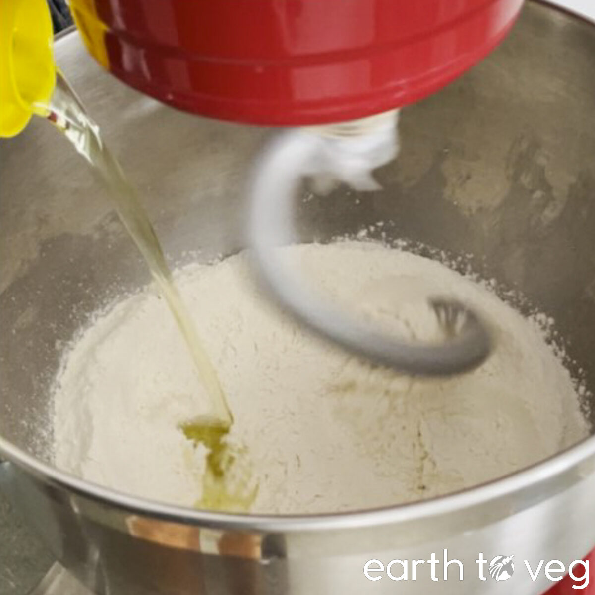 Grapeseed oil is poured onto flour in the mixing bowl.