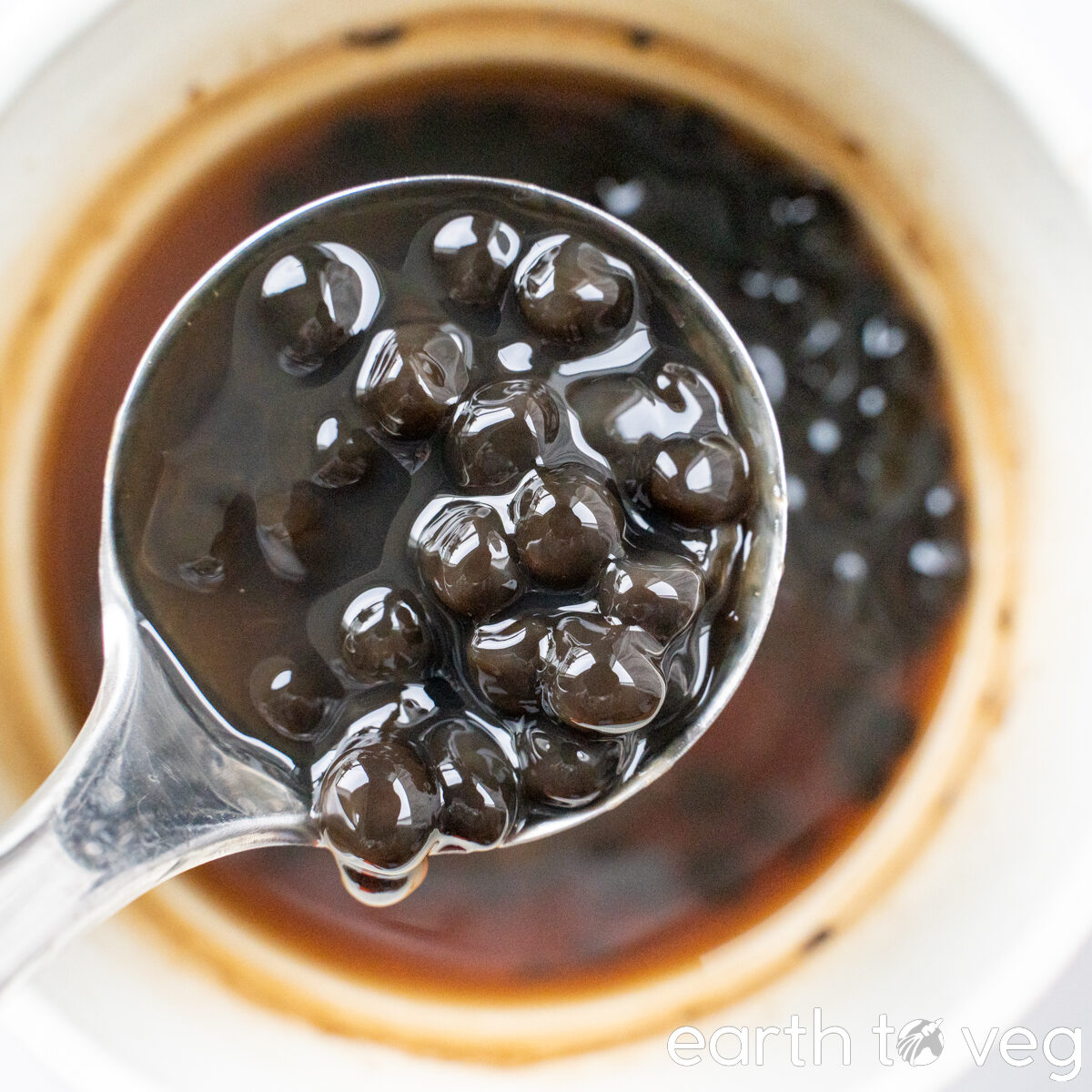 Black tapioca pearls in a metal ladle.