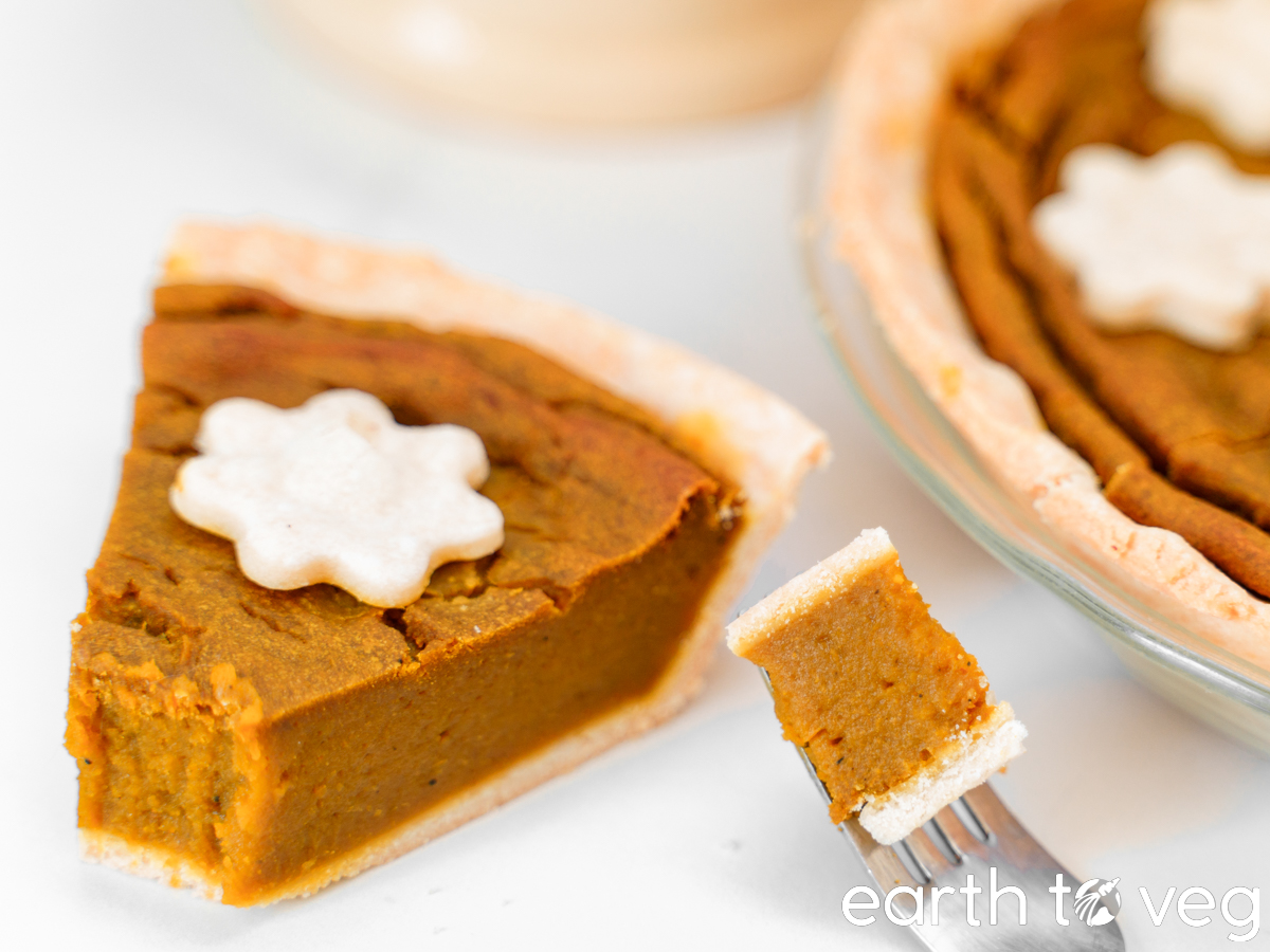 a slice of pumpkin pie with a chunk taken out by a fork, with more pie in the background