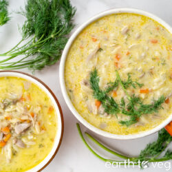 Two bowls of vegan avgolemono on a light background, with dill garnish.