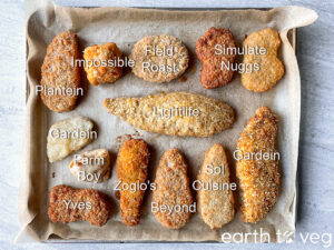 A top-down and labelled view of 13 different vegan chicken varieties, all laid out on a parchment paper lined baking sheet.