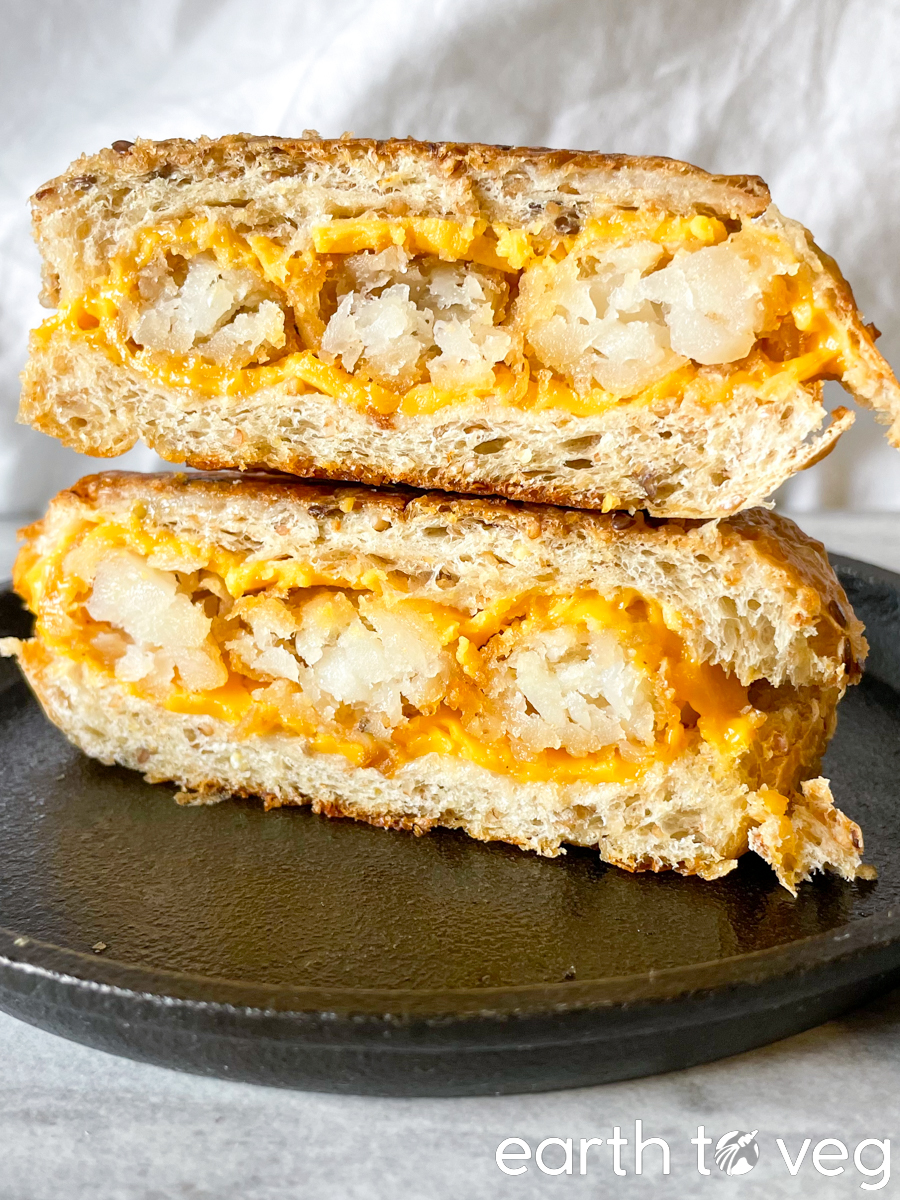 tater tot melt sliced in half stacked on top of each other in a cast iron skillet