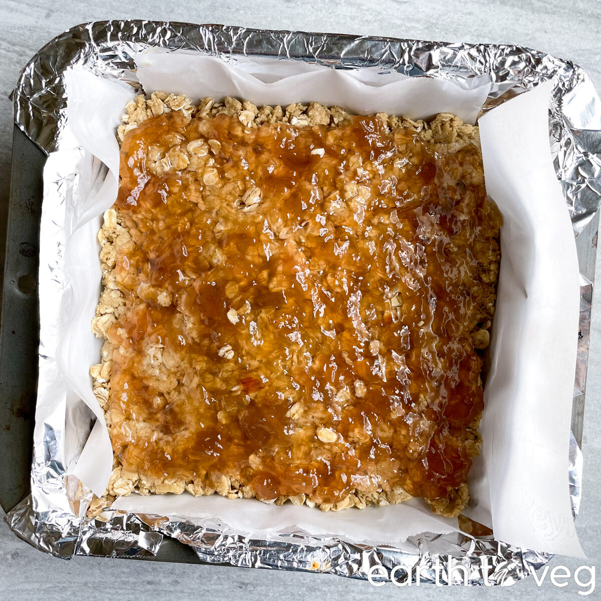 The rhubarb jam layer is spread evenly across the bottom oat-flour layer of the cake.