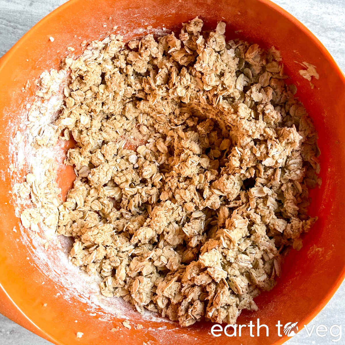 Oats and flour are added to the creamed butter mixture in the mixing bowl.