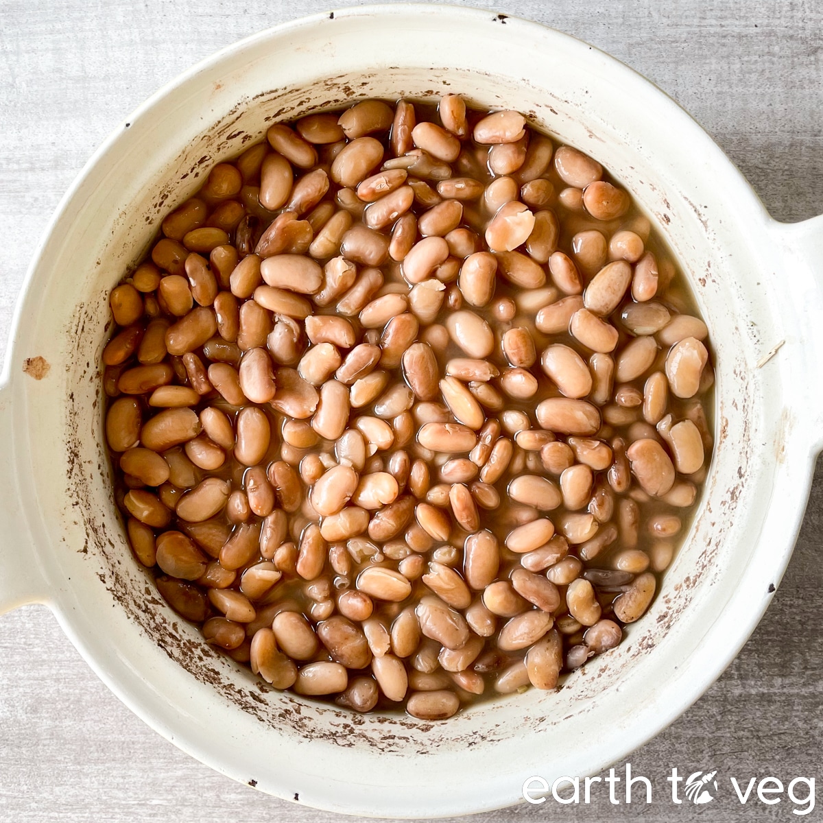 A pot full of freshly cooked frijoles de la olla on a grey countertop.