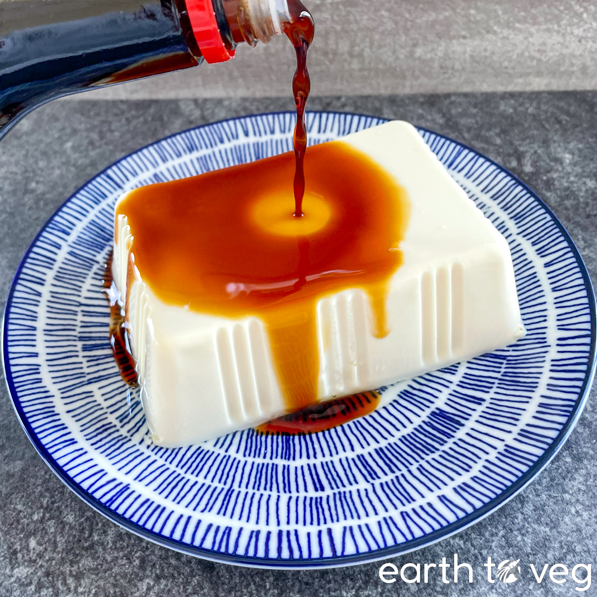 Kikkoman soy sauce is drizzled over a block of cold soft tofu.