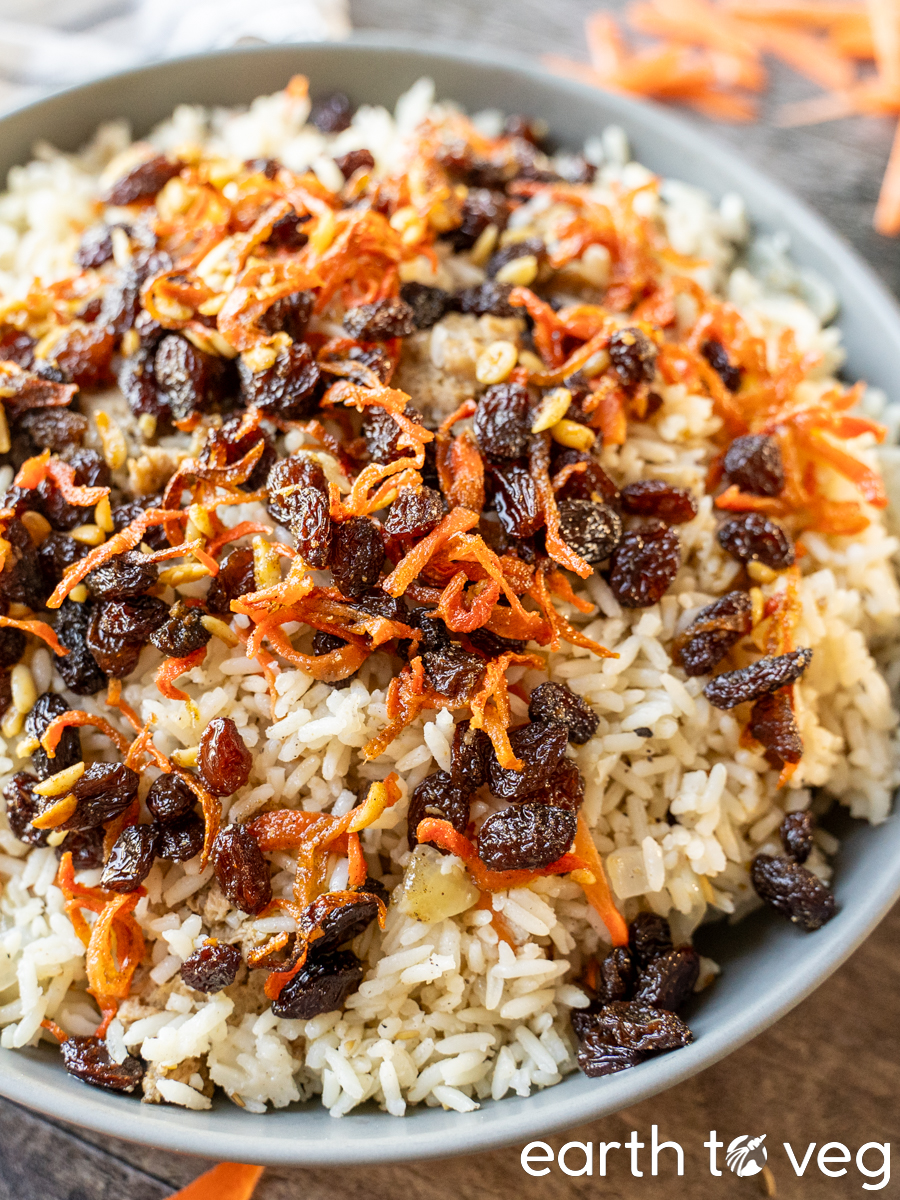 A plateful of vegetarian Kabuli Pulao rice, topped with crispy fried carrots and plump raisins.