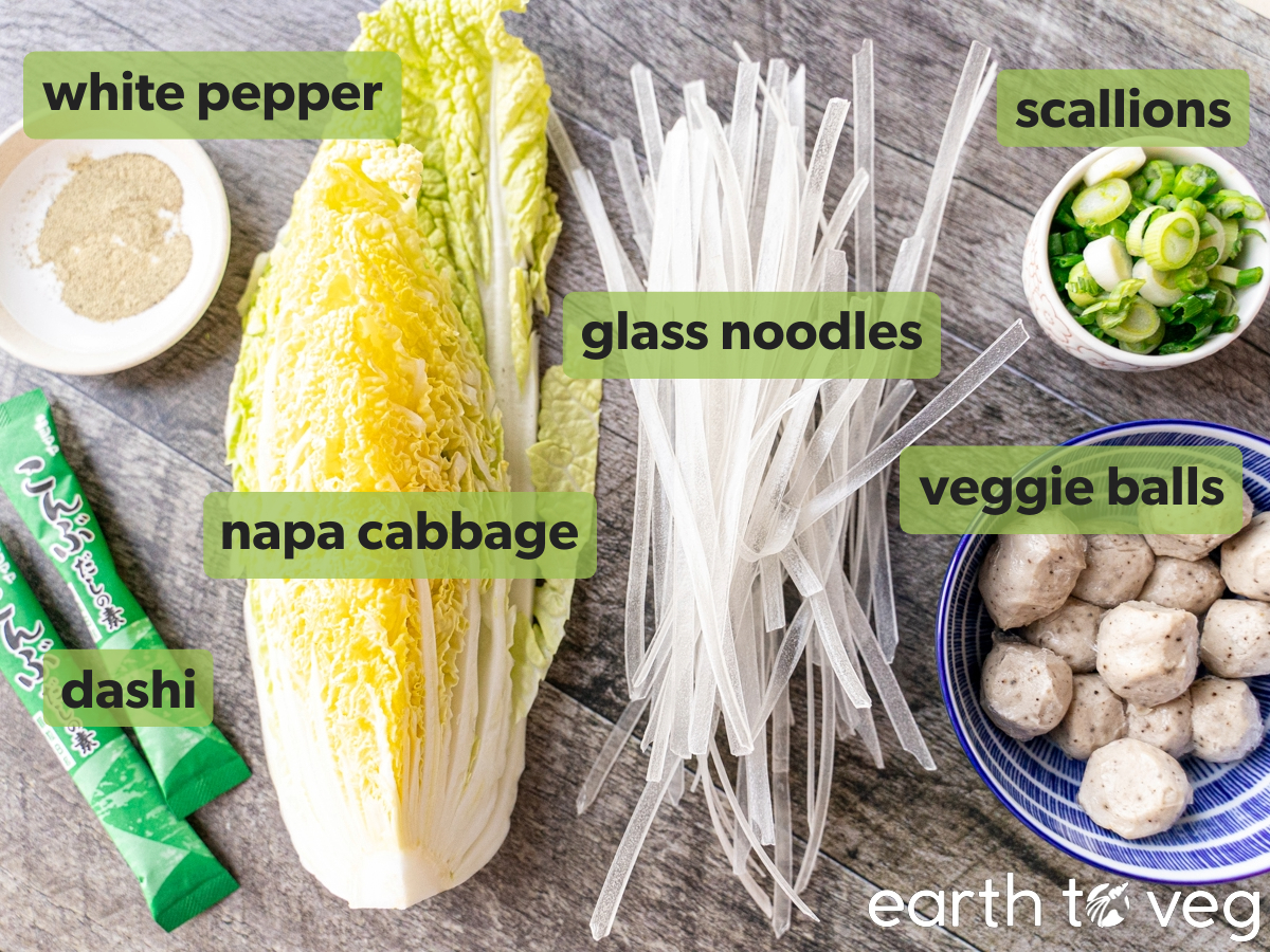 Ingredients for vegan fish ball soup, such as mushroom balls and glass noodles, are laid out on a wooden surface.