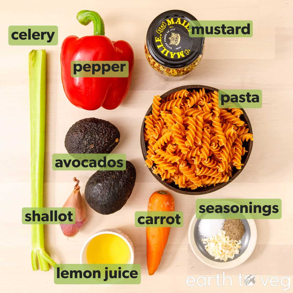 Ingredients for avocado pasta salad on a wooden table.