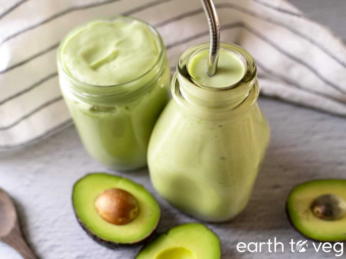 Two glasses of Vietnamese avocado smoothie on a grey tabletop.